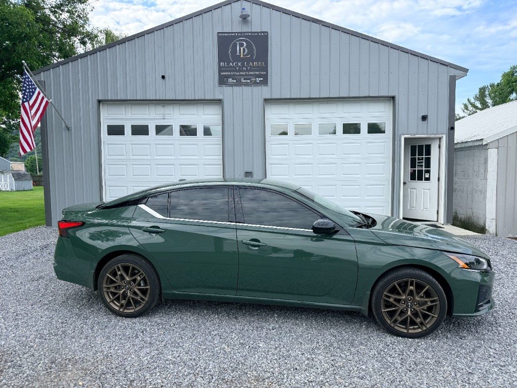 Dark green sedan with window tint parked in front of Black Label Tint in Glen Hope
