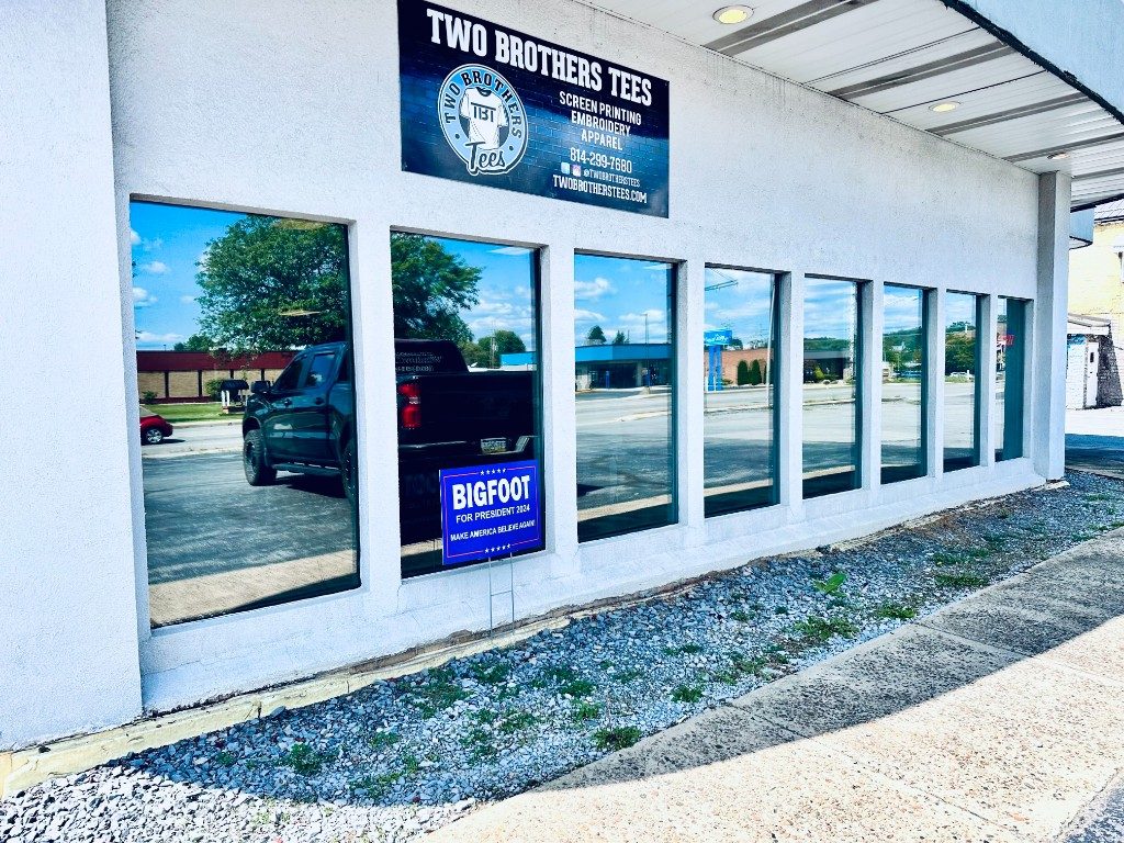 Row of commercial windows with reflective solar film on a white storefront