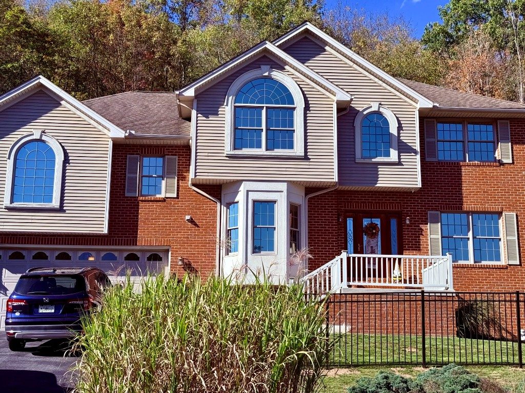 Suburban home with blue reflective residential window tint on bay and arched windows